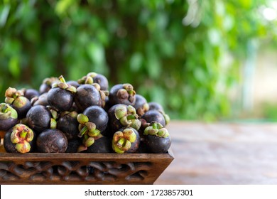 Purple mangosteen in basket on wooden table. Purple mangosteen is a tropical fruit which comes from the rainforests of South East Asia.