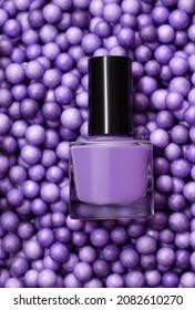 Purple nail polish bottle on purple balls background. Purple nail polish bottle on small purple balls texture