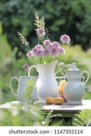 Purple onion flowers in a white jug and apricots