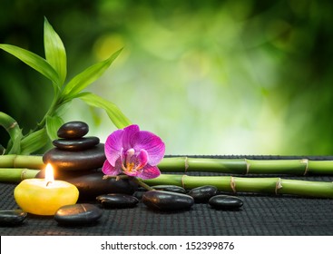 purple orchid, candle, with tower black stones , bamboo on black mat - Powered by Shutterstock