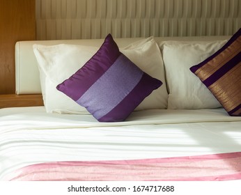 Purple pillow on white bed, closeup shot.