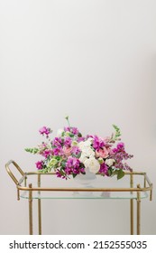 Purple Pink And White Flower Centerpiece In White Vase On Bar Cart