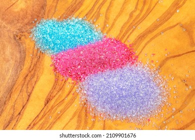 Purple, Red, And Turquoise Confectionary Sugar Over A Wood Background