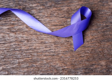 Purple ribbon for the awareness about the unacceptability of the violence against women on dark gray rustic wooden surface. Top view with space for text. Domestic violence awareness. - Shutterstock ID 2316778253