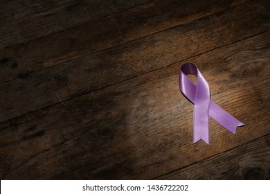 Purple Ribbon On Brown Wooden Background, Space For Text. Domestic Violence Awareness