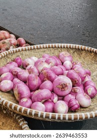 Purple shallots in a woven basket on a street, showcasing fresh organic produce in a rustic market setting.