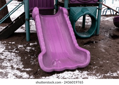 Purple slide on a dirty playground. Abandoned playground in a park in winter - Powered by Shutterstock