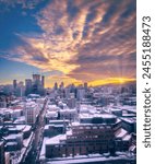 Purple sunset and colourful cloudscape above Saint-Catherine Street, downtown Montreal skyline covered in snow, and rays above Mount Royal, Quebec, Canada. Vertical winter photo taken in February 2023