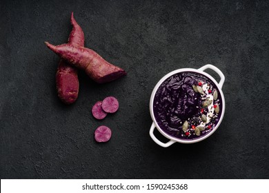 Purple Sweet Potato Cream Soup In Plate Overhead With Sour Cream, Pumpkin Seeds, Sesame And Cut Spicy Pepper Copy Space Top View Photo. Vegetable Sliced Pieces Near Tasty Dish On Black Background