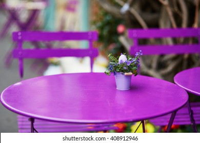 Purple table of Parisian outdoor cafe decorated with little bucket, flowers and Easter egg