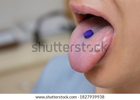 Purple tablet for indicating plaque on the tongue of a woman