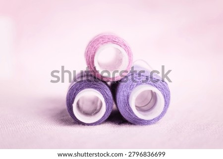 Purple thread spool and white tape on soft background, sewing, t