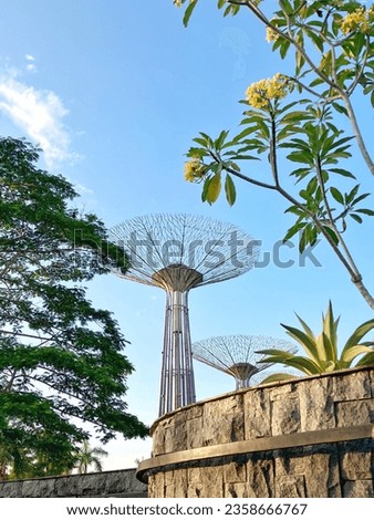 A purple tower covered by trees and flowering plants.