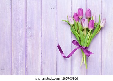 Purple tulips over wooden table. Top view with copy space
