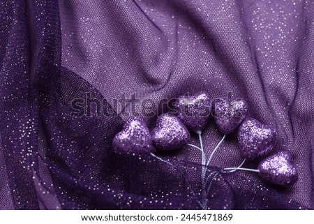 Purple tulle with purple hearts  texture. Lilac fabric background with small hearts. Elegance mesh tulle fabric. Background for holiday.