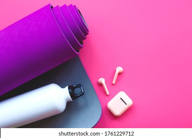 purple yoga mat, water bottle and headphones on a pink background. - Powered by Shutterstock