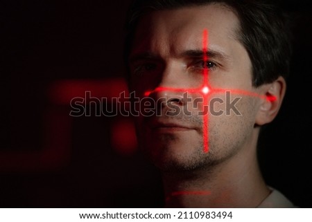 Purpose, technology and human, concept. A young man with projections of red patterns on his face, scanning, verification or interaction with augmented reality.