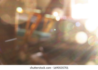 A Purposefully Blurry, De-focused Background Of A Green And Gold Chair In A Bedroom Filled With Bright Light And Warm Glowing Colors Shining From The Window. 