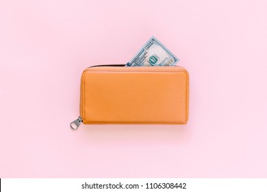 Purse with hundred dollar banknotes on pink background. Flat lay, top view, copy space 