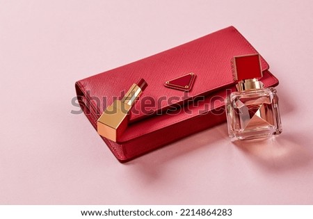 Purse, lipstick ans perfume on pink background