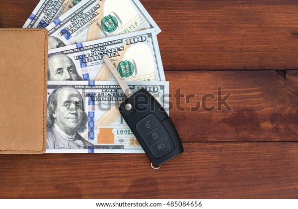 Purse with money and car keys lay on a wooden board.\
Concept credit car loan