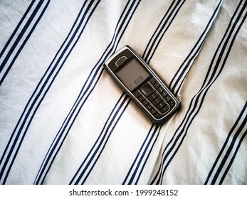 Push button, simple, black mobile phone on white, striped textile.