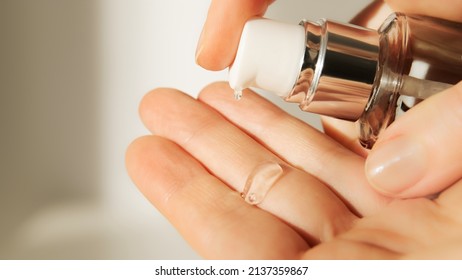Push dispenser liquid facial fluid gel squeezed out to hand. Cosmetologist pours clear cleansing moisturizing hyaluronic serum acid. Cosmetic concept.