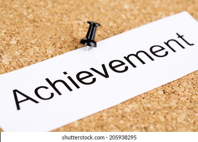 Push pin on paper with word achievement on cork board