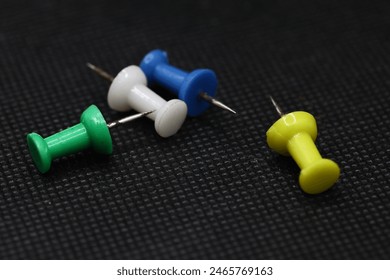 Push pins are small, thumbtack-like objects with a pointed end and a flat head, typically used to fasten items like papers or posters onto surfaces such as corkboards or walls