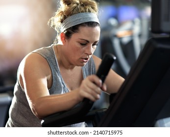Push yourself and keep it going. Shot of a determined looking woman working out on an elliptical machine in the gym. - Shutterstock ID 2140715975