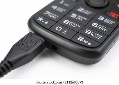 Push-button mobile phone while charging. On white background. 