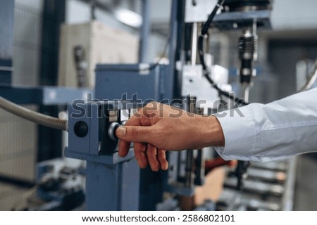 Pushing the button of machine. Close up view of man that is working in the modern factory.