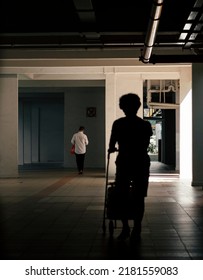 Pushing Groceries Cart At Void Deck Of HDB Flat In Shadow And Light