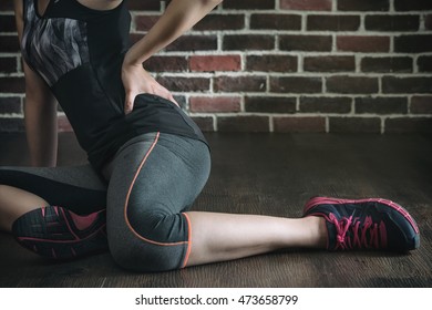 Pushing Her Body Too Far Got Low Back Pain In Fitness Exercise Training, Healthy Lifestyle Concept, Indoors Wooden Floor Brick Wall Background