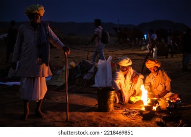 Pushkar, India - November 6, 2019: Indian Rural Village Men And Camels Lit By Camp Fire In Night At Pushkar Camel Fair Pushkar Mela - Annual Famous Camel And Livestock Fair And Tourist Attraction