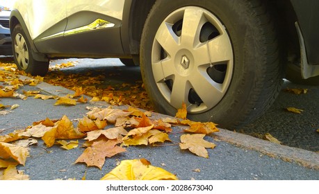 Pushkin, Russia - October, 2020: Renault Car wheel on road. Yellow fallen maple leaves on asphalt. Golden autumn street. Travelling. Driving. Automobile hubcap. Protection auto. Fall. Vehicle tire.