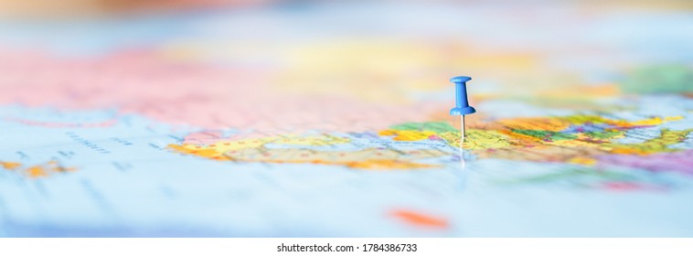 Pushpin showing the location of a destination point on a map. Travel destination, pin on the map. Very selective focus, blur on all edges and special lightening. Blue pushpin