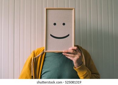 Put a happy optimistic face on, happiness and cheerful emotions concept, man holding picture frame with smiley emoticon printed. - Shutterstock ID 525081319