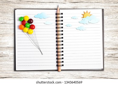 Put multicolor candy (draw line for balloon) and paper craft put on note book on wood  background., With zine culture.  - Powered by Shutterstock