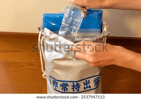 Put a plastic bottle of drinking water in a emergency bag, (translation) The Japanese text written on the outside of the bag means 