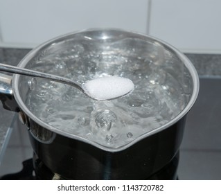 Put Salt With Spoon In Boiling Water In Pan