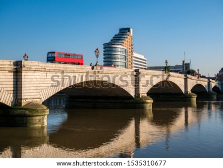  Putney bridge reflected in Thames river water in a sunny day - London, England