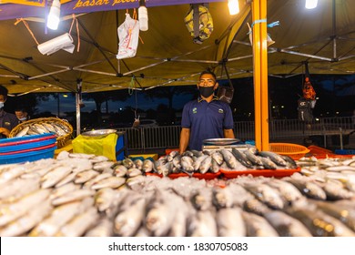 Putrajaya, Malaysia - October 09, 2020: Street food night market at  Putrajaya, near Kuala Lumpur. Salesman with face mask in a seafood street store. The fish are lying on the counter in front of him