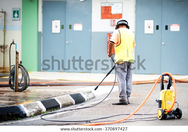 PUTRAJAYA,MALAYSIA - 26 JAN 2016 - Foreign\
worker cleaning road curve at sunny day. Putrajaya is the new\
administrative capital of\
Malaysia