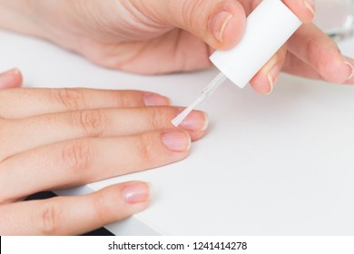 Putting Clear Varnish On Finger Nails On A White Background