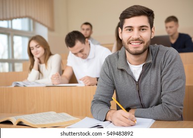 Putting in the effort. Handsome young guy smiling to the camera during the lecture at his university studying in the classroom happiness smart education exam college high school concept copyspace 