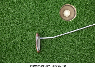 Putting Golf Club On Green Grass With Golf Ball In The Hole - Top View