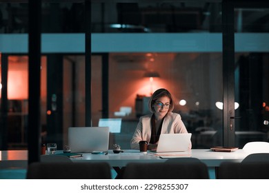 Putting her career first. a businesswoman using a laptop at her desk during a late night at work.