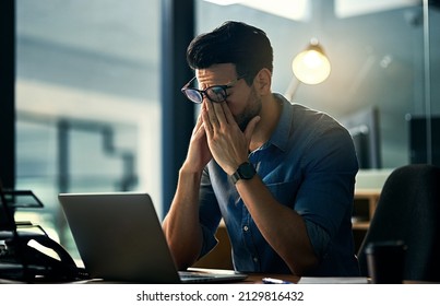 Putting His Career First And His Health Second. Shot Of A Young Businessman Experiencing Stress During A Late Night At Work.