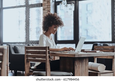 Putting ideas into something real. Beautiful young African woman in smart casual wear working using computer while sitting in cafe - Shutterstock ID 617984456